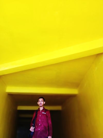 Low angle portrait of man standing against yellow ceiling