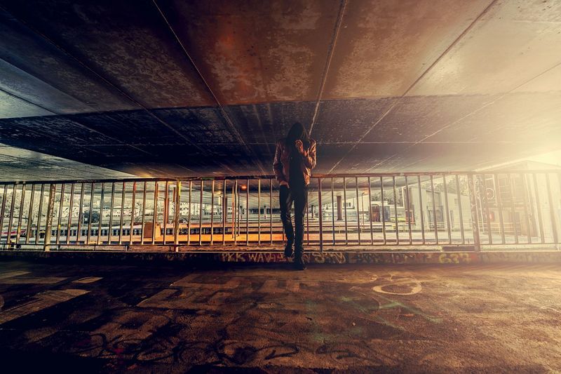 Man standing below bridge in city