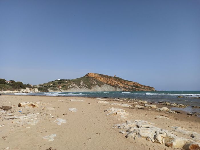 Scenic view of beach against clear blue sky