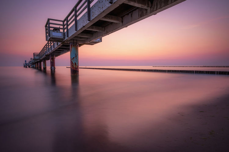 Bridge over sea against sky during sunset