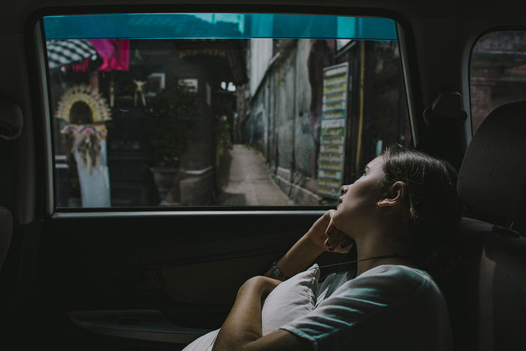 A young girl looks out of the window of a car in seminyak bali