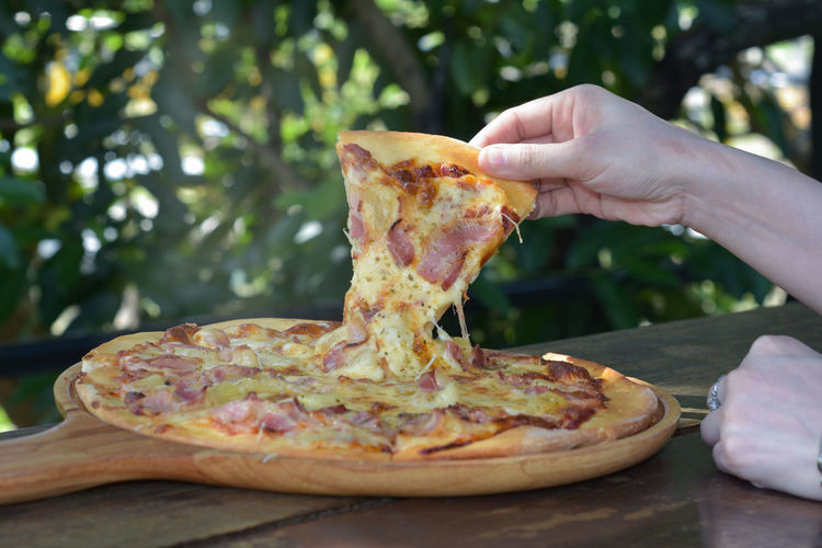Cropped hand of woman holding pizza