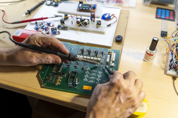 Senior man working on electronic circuits in his workshop, close up