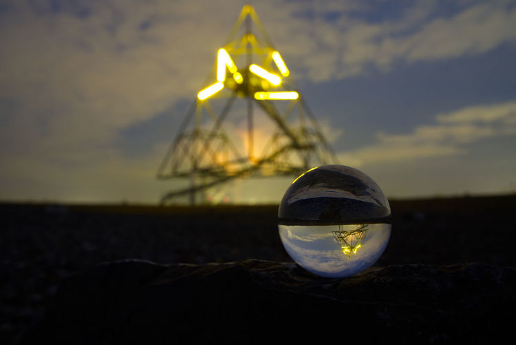 Close-up of crystal ball on field against sky during sunset