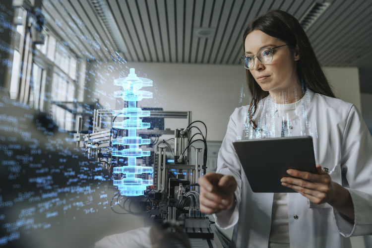 Female engineer with digital tablet examining development of industrial product