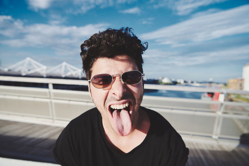 Portrait of young man wearing sunglasses against sky during golden hour
