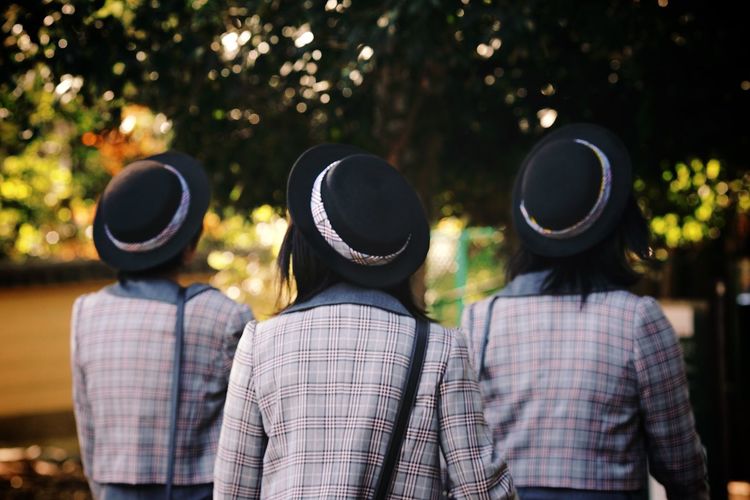 Rear view of female students walking against trees