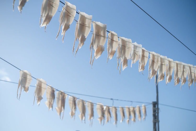 Low angle view of clothes drying on clothesline against clear blue sky