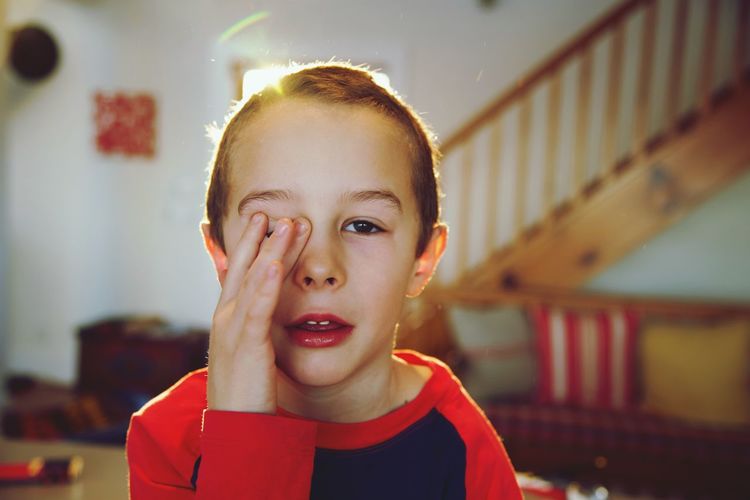 Portrait of boy rubbing eyes at home