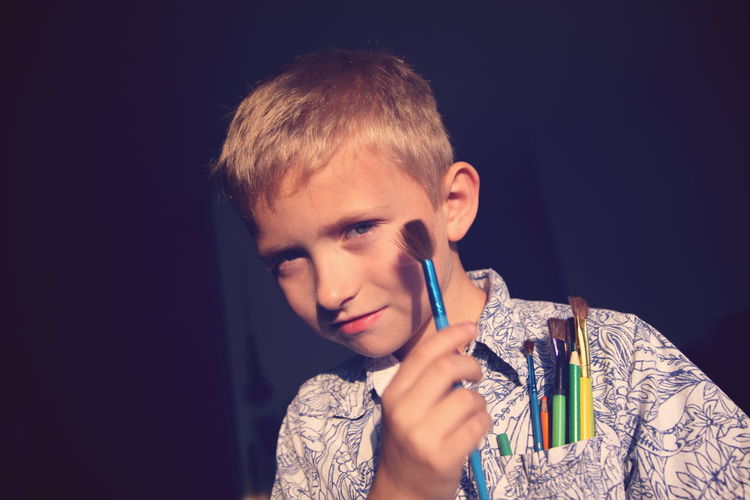 Portrait of boy holding paintbrush at home