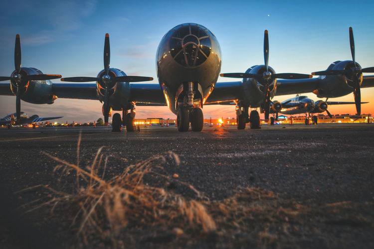 Airplane on airport runway against sky during sunset