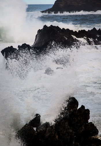 Scenic view of waves splashing on rocks in sea