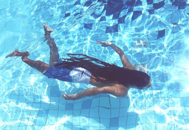 High angle view of man with dreadlocks swimming in pool