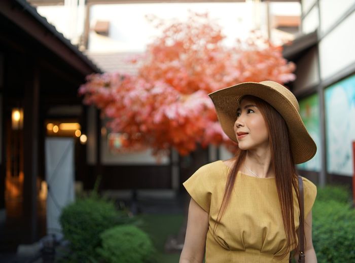 Woman looking away while standing against trees