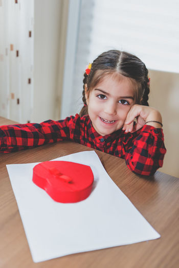 Portrait of smiling girl with heart shape gift at home