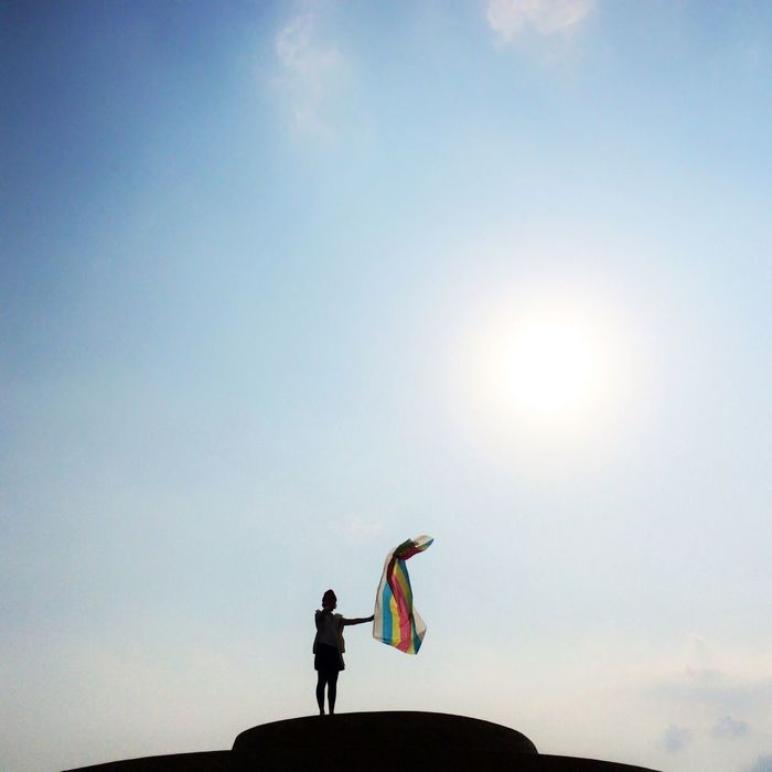 Low angle view of silhouette woman with colorful cloth against sky