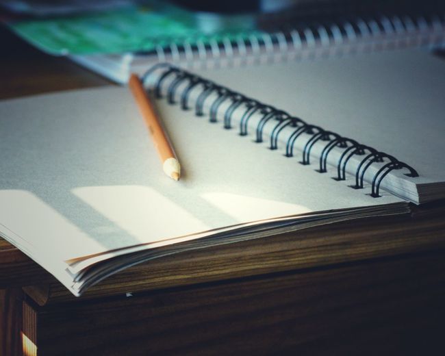 Close-up of pencil with book on table