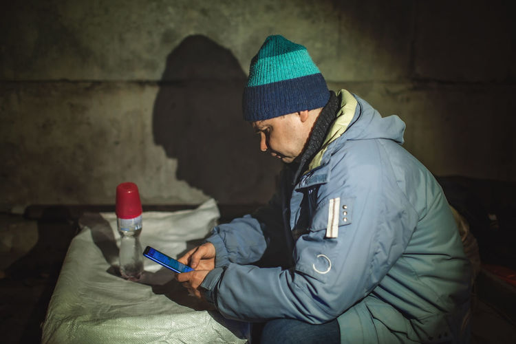 Ukrainian civil man sits in bomb shelter and reads latest braking news about russian invaders