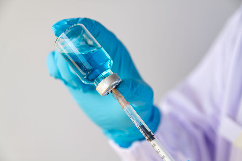 Close-up of doctor holding syringe against white background
