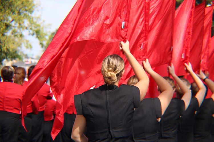 Rear view of women with red flags at event in city