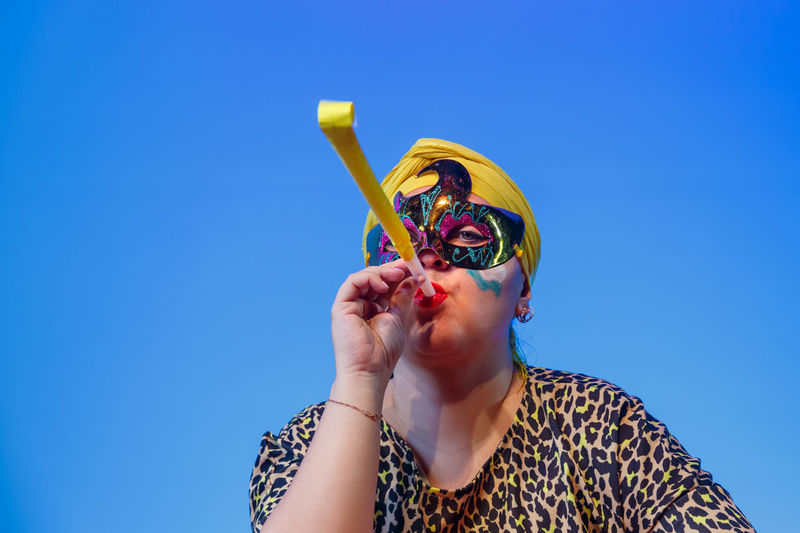 Low angle view of young woman wearing sunglasses against blue background