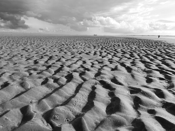 Footprints on sand at beach against sky