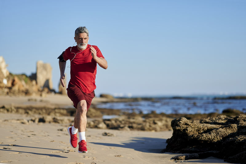 Determined man running on beach during sunny day