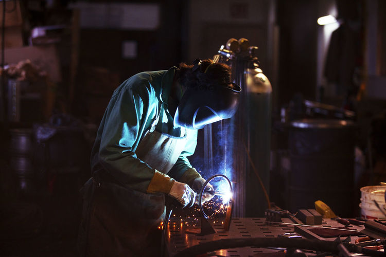 Side view of manual worker welding in workshop