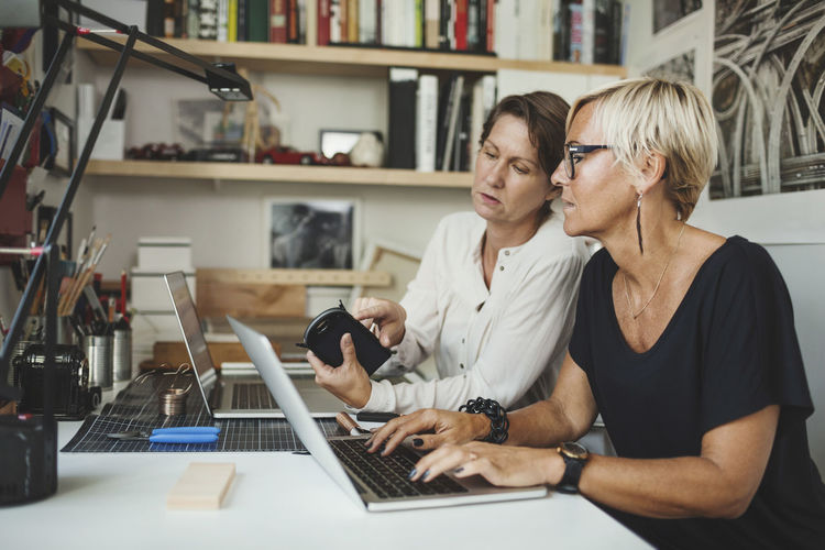 Female designers discussing over solar product at home office