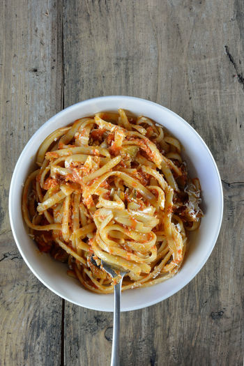 Linguine with tomato sauce and grated cheese on wooden table
