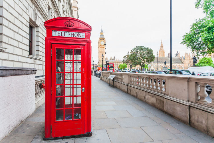 Red telephone booth on sidewalk in city