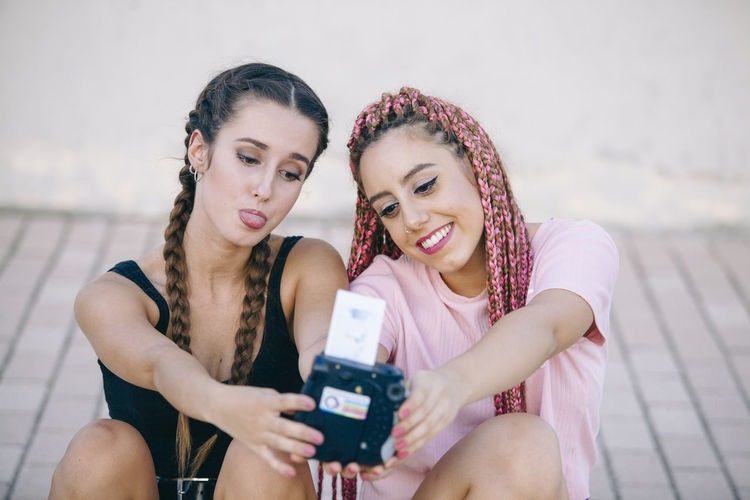 Happy friends taking selfie with vintage camera