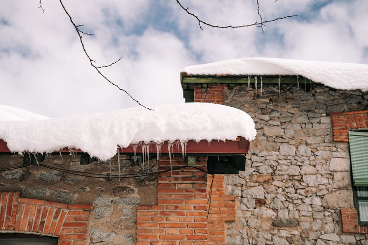 Built structure on snow covered house against sky