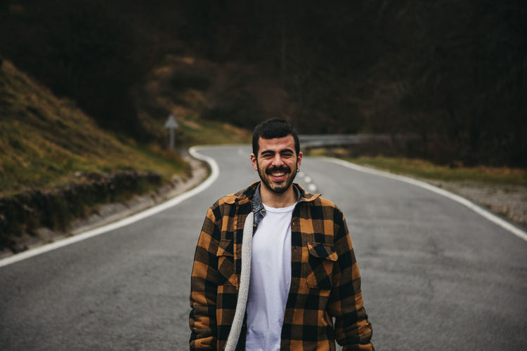 Portrait of smiling young man standing on road