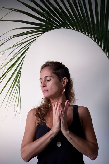 Beautiful woman practicing yoga at home with palm leaf