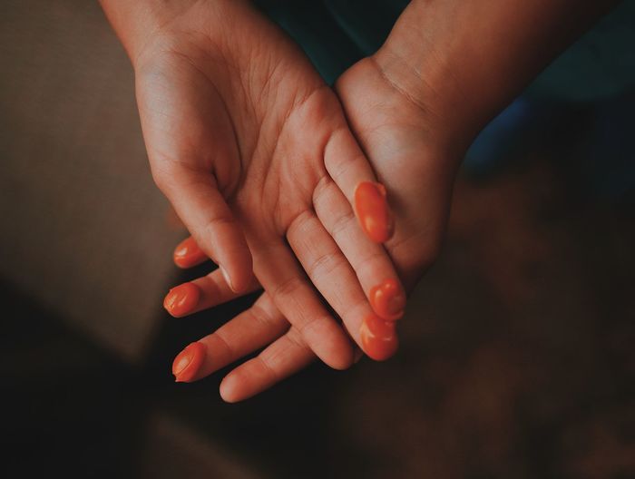 Cropped hands of fingers with orange cream