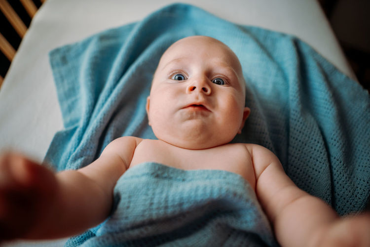 Baby toddler taking a selfie in crib. holding smartphone. scared face