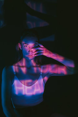 PORTRAIT OF BEAUTIFUL YOUNG WOMAN IN ILLUMINATED DARKROOM