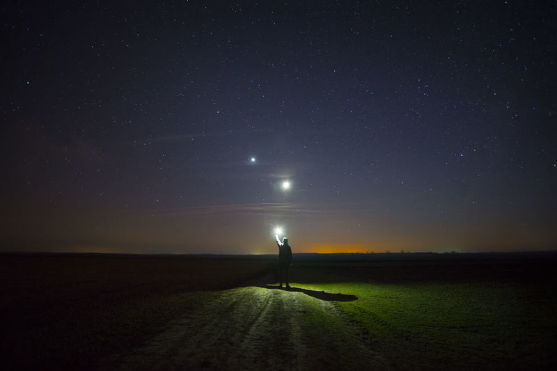 SILHOUETTE PERSON STANDING ON FIELD AGAINST SKY DURING NIGHT