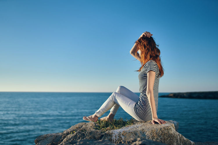 Man looking at sea against clear blue sky