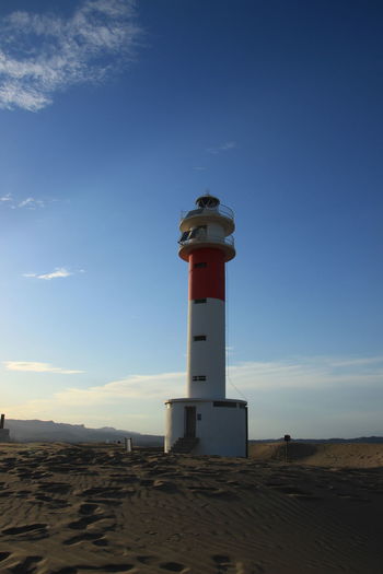 Sunset on a beautiful beach with a lighthouse, sunset with clouds.