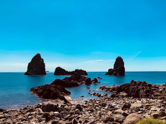 Scenic view of rocks in sea against blue sky