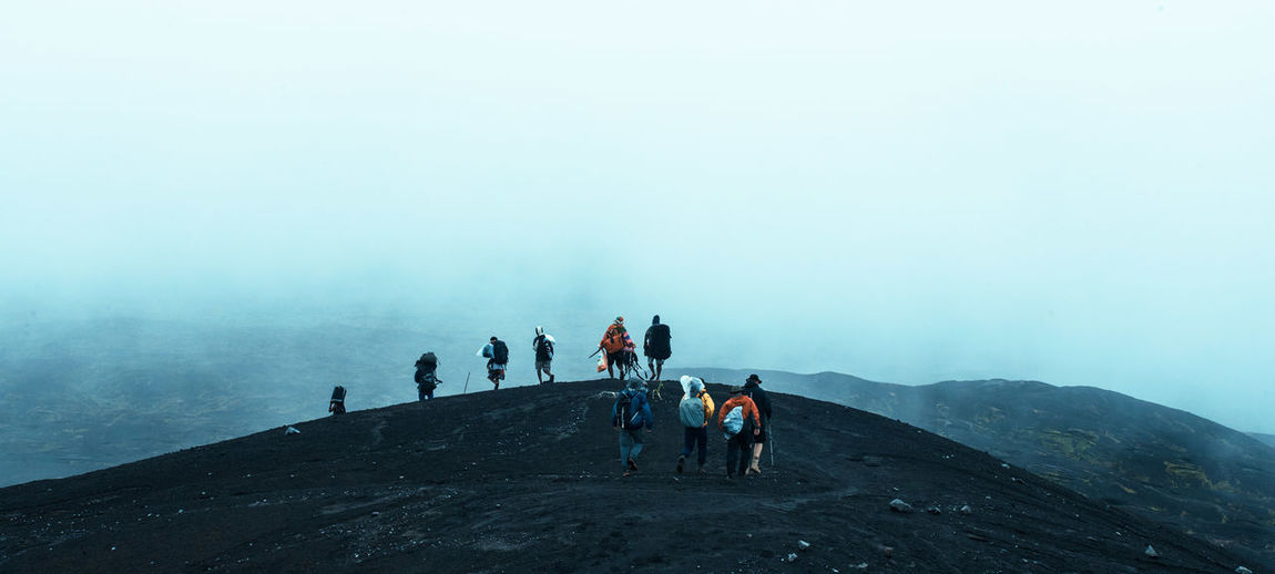 People hiking on mountain during foggy weather