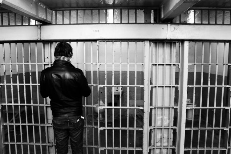 Rear view of prisoner standing in jail