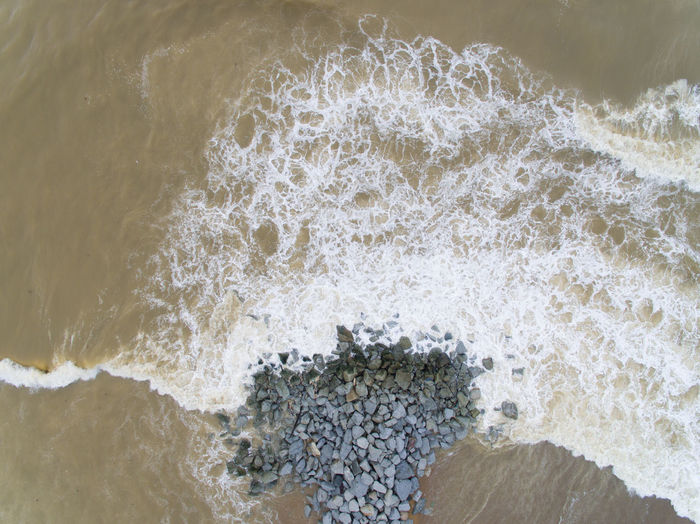 Aerial view of a beach with wave, rocks and wave breaker