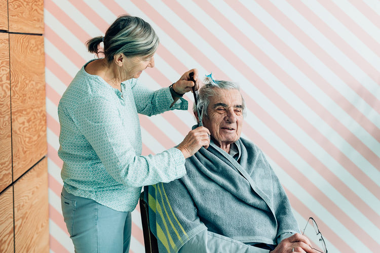 Elderly lifestyle. woman taking care of an old man. haircut in a barbershop or hospice or home