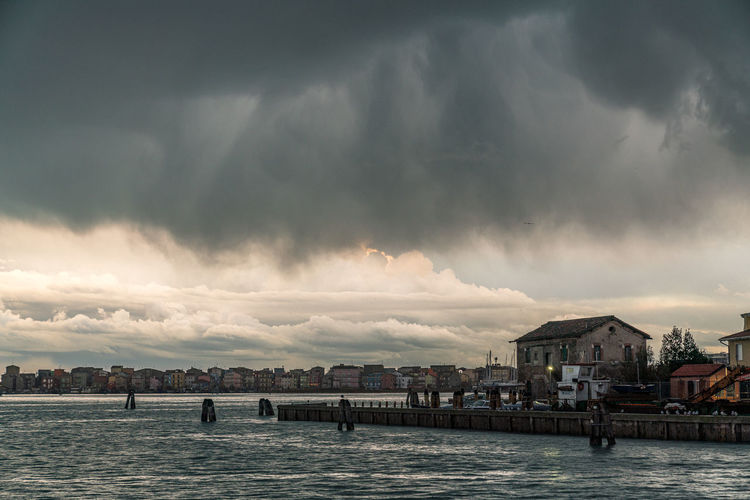 Panoramic view of sea and buildings against storm clouds