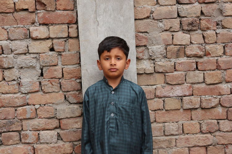Portrait of man standing against brick wall