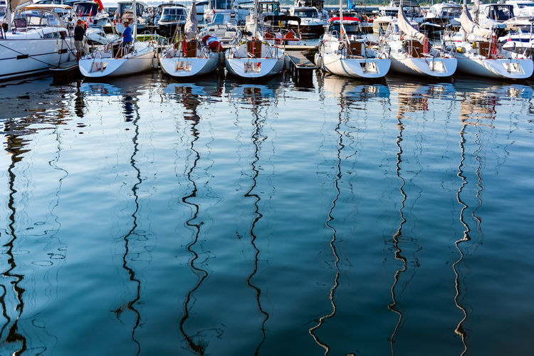 Sailing yachts moored on a pier in a harbour on baltic sea and reflection in the water. 