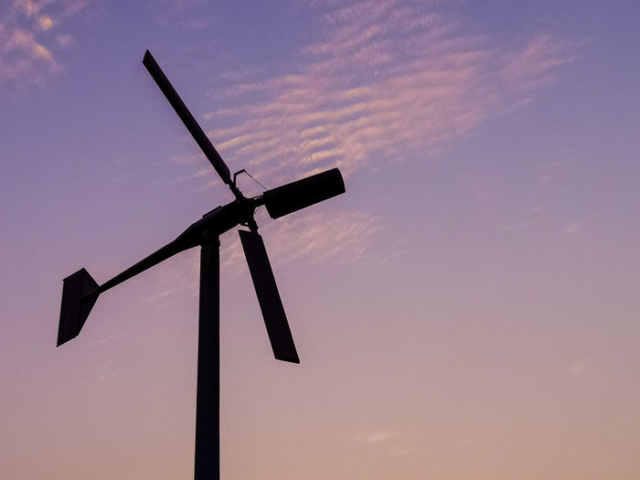 Low angle view of wind turbine against sky during sunset